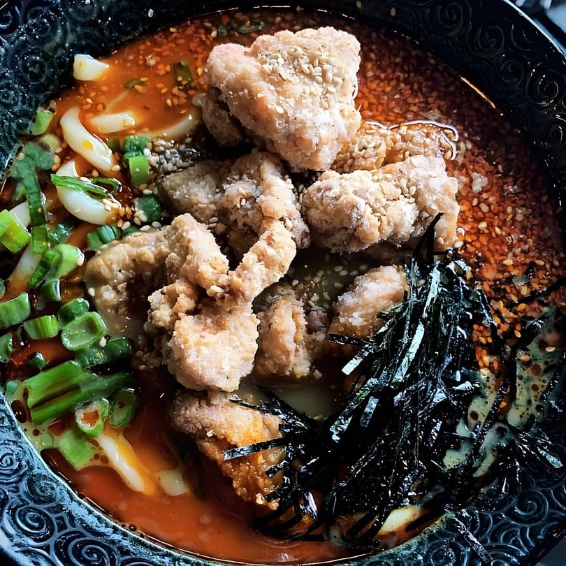 Tonkotsu ramen with crispy fried chicken, green onions, nori, and sesame seeds in a rich broth.